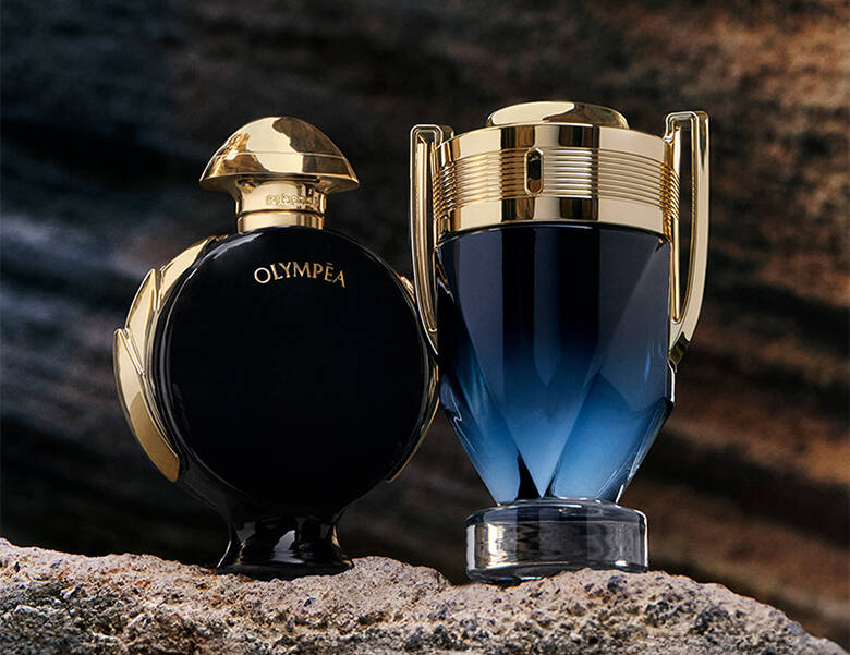 Her ses to forskellige parfumer fra Rabanne. Den ene er guld og blå og den anden er guld og sort. Baggrunden er nogle klipper. 