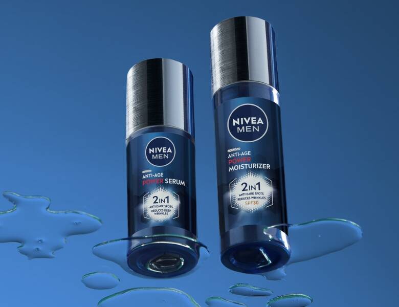 Her ses en blå baggrund med to mørkeblå og grå Nivea produkter. Billedet er taget skråt nedefra.