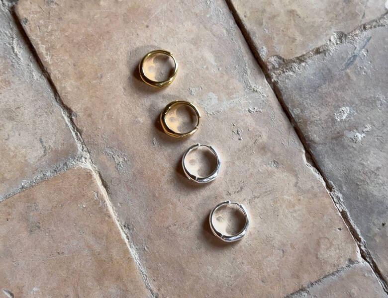 Her ligger fire øreringe - et par i guld og et par i sølv på en mursten.