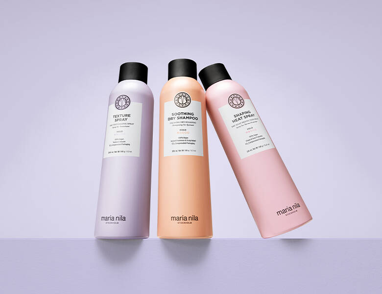 Her ses en lyslilla baggrund med tre Maria Nila produkter - et lilla, et orange og et lyserødt.