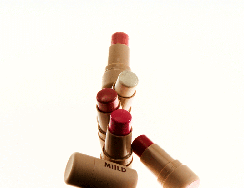 Her ses flere blush-sticks fra MIILD samlet i en klynge mod en lys, neutral baggrund. Produkterne er i beige emballage med forskellige nuancer af blush i toppen, herunder rosa, koral og bærfarvede toner.