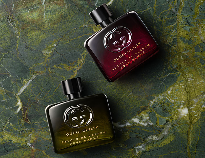 Her ses en grøn baggrund med to liggende Gucci parfumer i grøn og rød. 