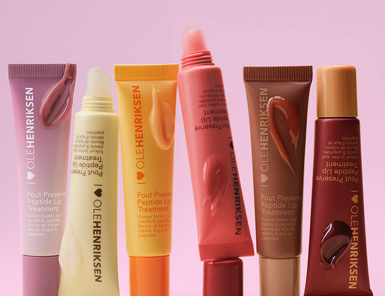 Her ses OLE HENRIKSEN læbeprodukter i forskellige farver på en lyserød baggrund.