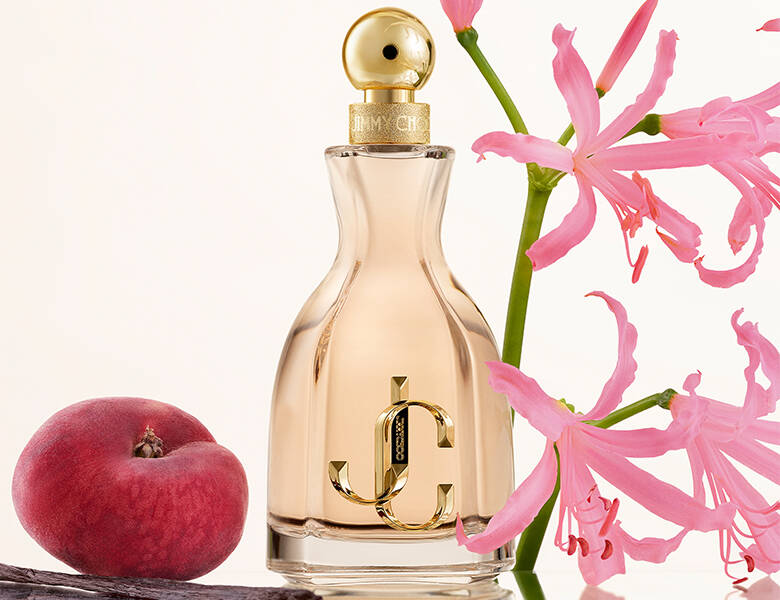 Her ses en hvid baggrund med et rødt æble i venstre og en lyserød blomst i højre. I midten ses en lyserød Jimmy Choo parfume. 