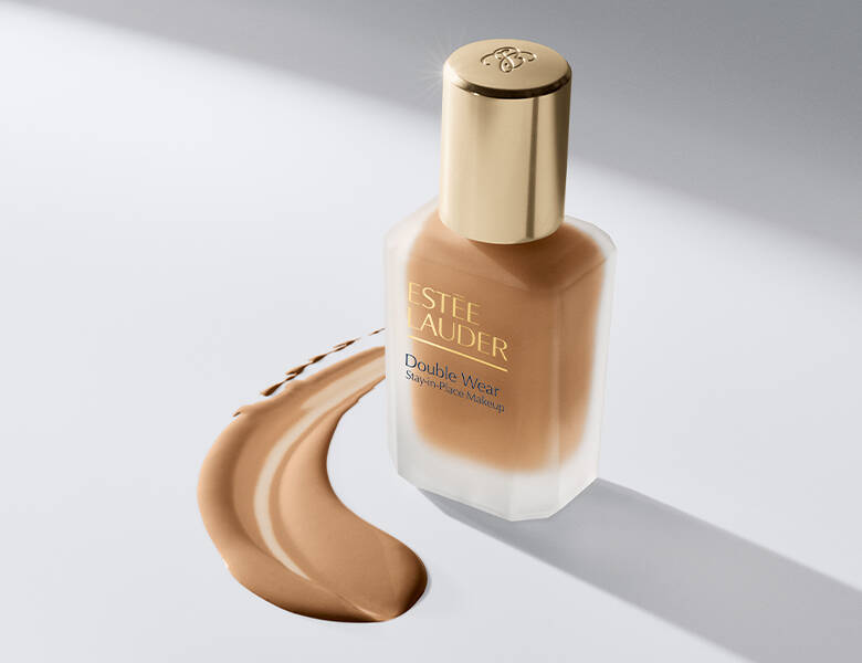 Her ses en Estée Lauder Double Wear Foundation på en lys baggrund, hvor noget er produktet er smurt ud på.