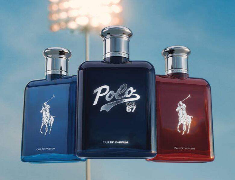 Her ses et billede med tre parfumeflakoner fra Polo Ralph Lauren placeret side om side mod en blå baggrund. På den midterste flakon står teksten “Polo EST 67”, mens de to andre har det klassiske polo-logo. Flakonerne er i blå og rød nuance med sølvfarvede låg.