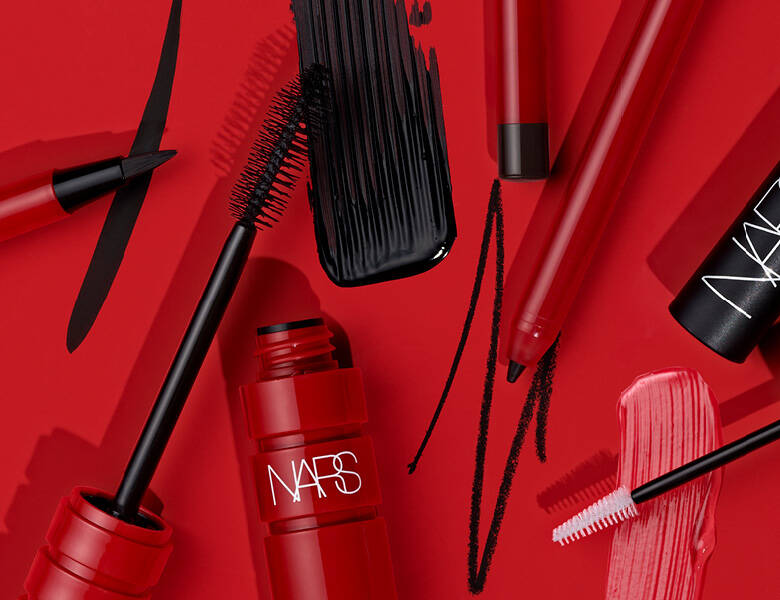 Her ses en rød baggrund med mange forskellige øjenprodukter fra Nars. 