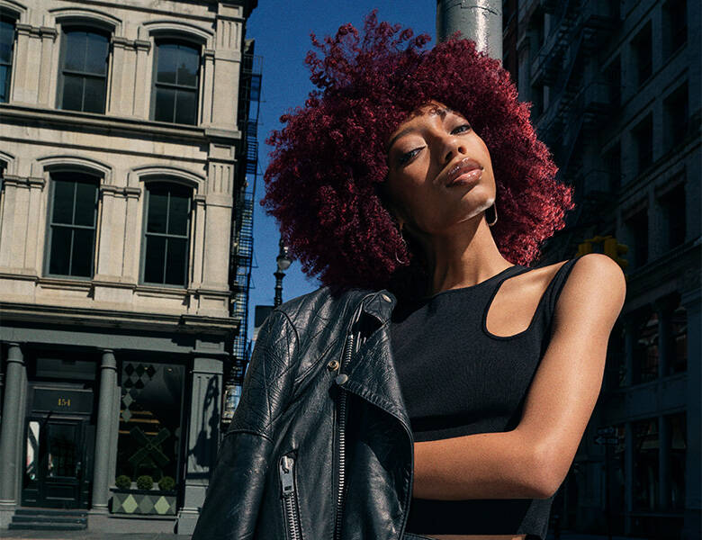 Her ses en mørk baggrund med en kvinde, som har rødt krøllet hår. 