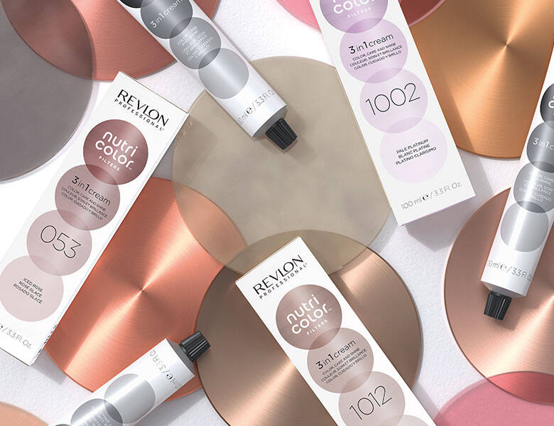 Her ses forskellige Revlon Professional produkter, som alle har prikker på. Baggrunden har store prikker i de samme farver som produkterne. 
