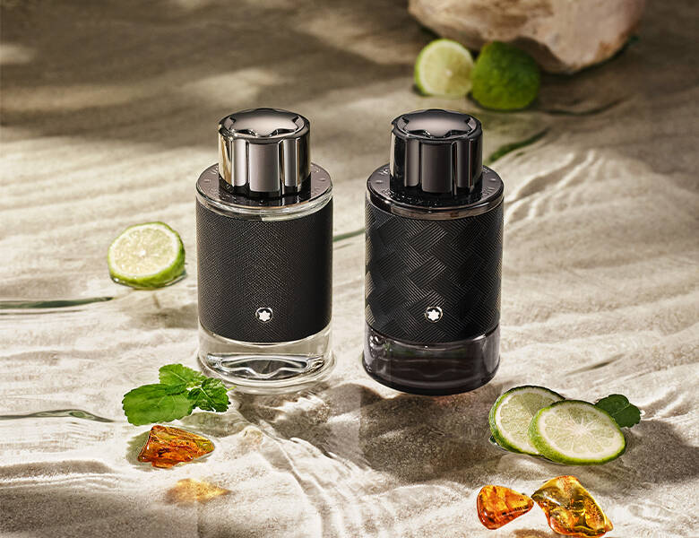 Her ses to sorte parfumer stående i klart vand med planter og lime. 