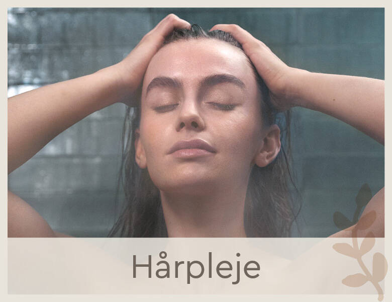 Her ses et billede af en kvindes ansigt. Kvinden står i badet og rører ved sit våde hår. Hun ser afslappet ud. 