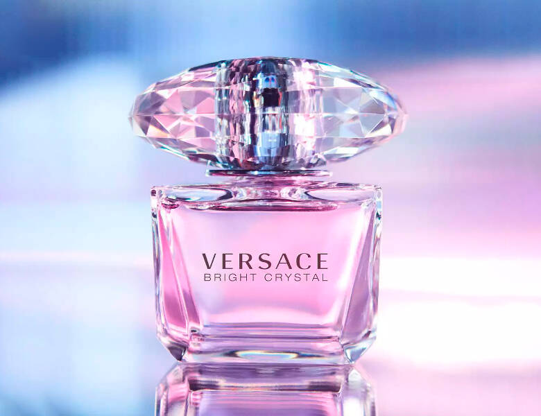 Her ses en lilla og blå baggrund med en lilla Versace parfume. 