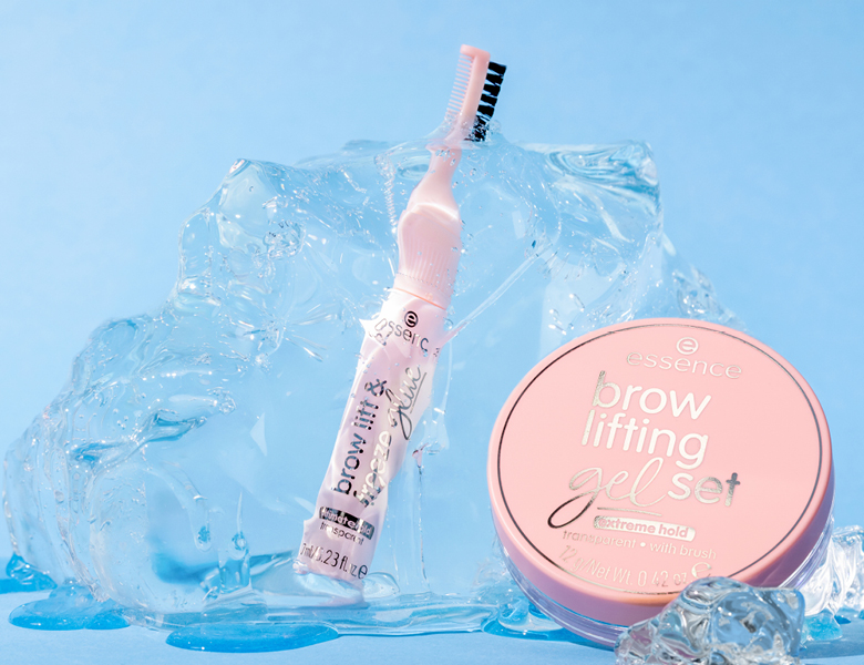 Her ses et billede med to øjenbrynsprodukter fra essence placeret mod en blå baggrund med is- og gelelignende teksturer. På produkterne står teksten “essence brow lifting gel set” og “extreme hold”.