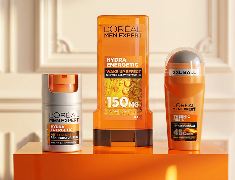 Her ses tre L’Oréal Men Expert-produkter fra Hydra Energetic-serien på en orange sokkel: ansigtscreme, shower gel og antiperspirant.
