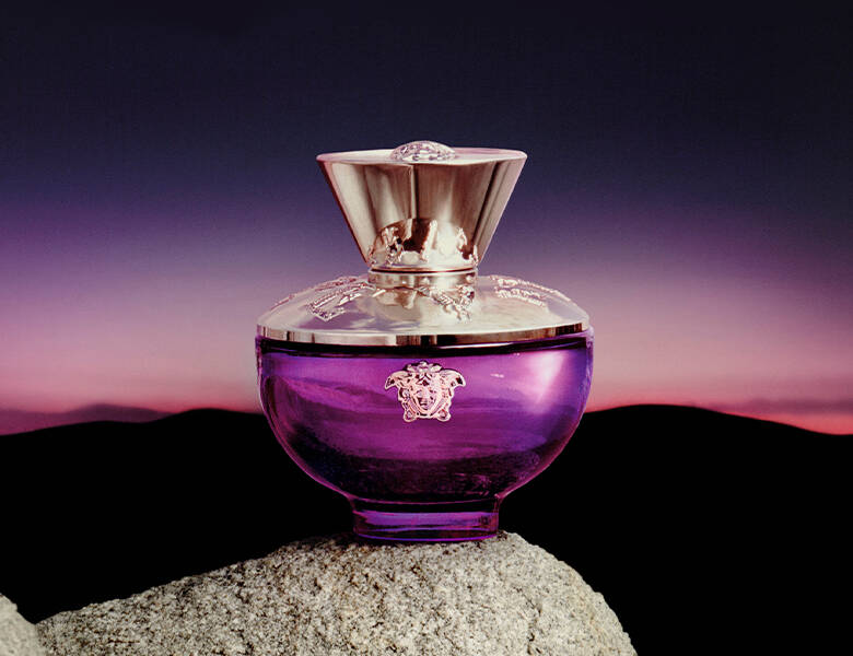 Her ses en sort, lilla og lyserød baggrund med en lilla Versace parfume. 