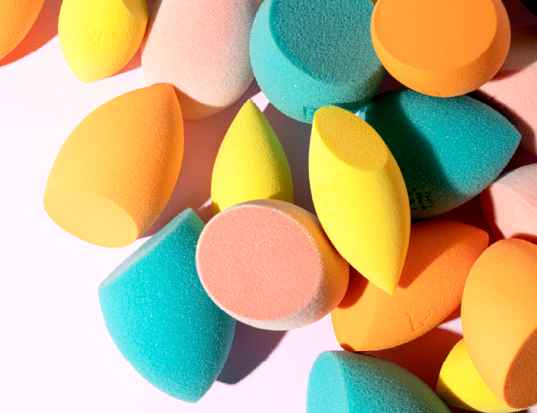Her ses en lys baggrund med en bunke af farverige Real Techniques makeup sponges.