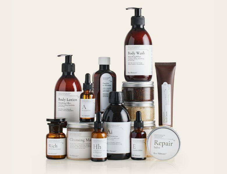 Her ses et antal af Raz Skincare produkter på en lys gul baggrund. Produkterne står på hinanden.
