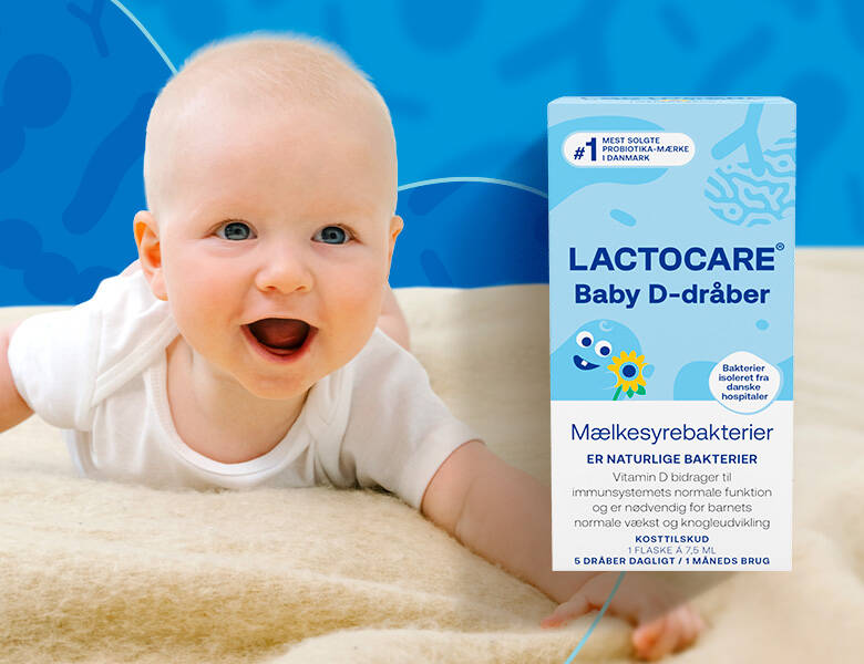 Baby på lyst uldtæppe med blå baggrund. Der ses Lactocare D-dråber forrest i billedet.