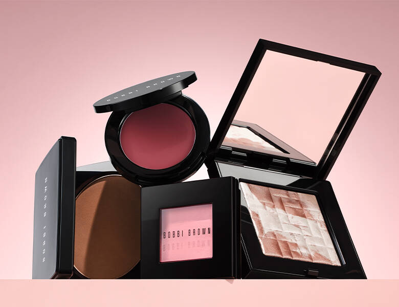 Her ses en sart lyserød baggrund med forskellige makeupprodukter.