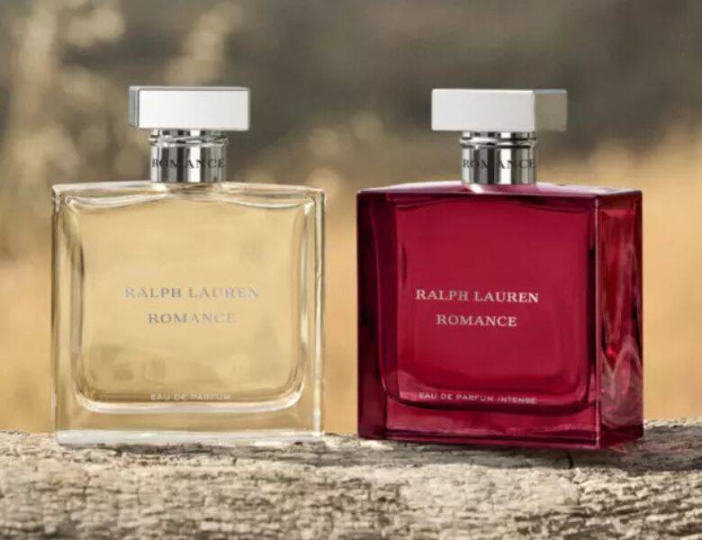 Her ses et billede med to parfumeflakoner fra Ralph Lauren placeret side om side. På begge flakoner står teksten “RALPH LAUREN ROMANCE”, og på den røde flakon står også “EAU DE PARFUM INTENSE”. Flakonerne er i henholdsvis klar og rød nuance med sølvfarvede låg og er placeret på en træoverflade med en sløret naturbaggrund.