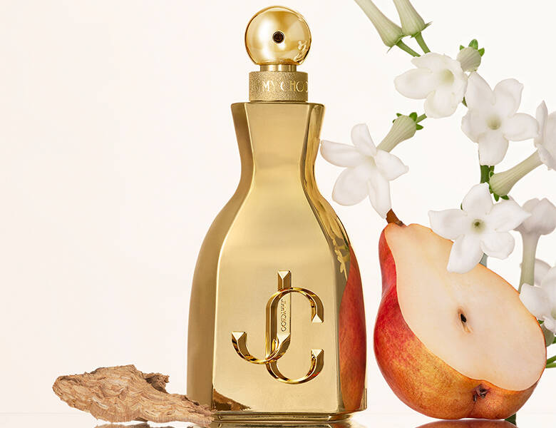 Her ses en hvid baggrund med nogle hvide blomster og en åben pære. I midten er en guld parfume. 