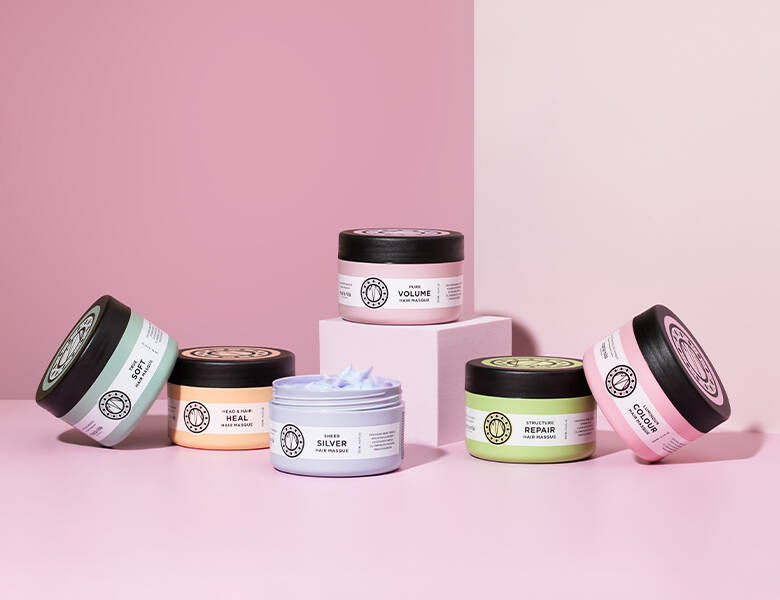 Her ses en lyserød baggrund med seks forskellige Maria Nila produkter i forskellige farver. 