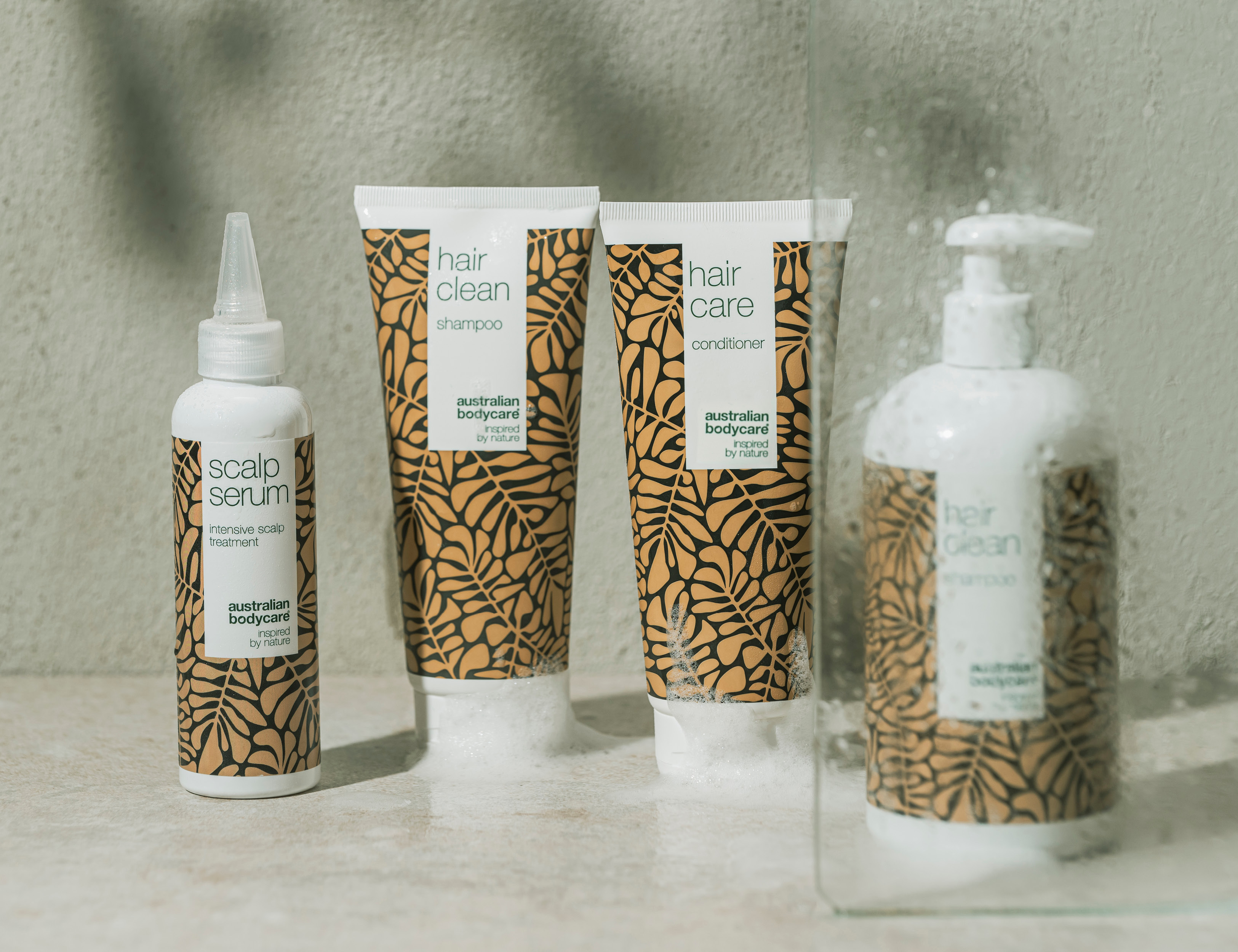 Her ses australian bodycare hårprodukter – shampoo, conditioner og scalp serum placeret i et badeværelsesmiljø.