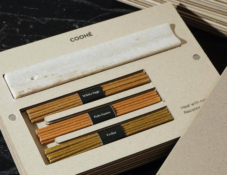 Coohe røgelsessæt i åben æske med røgelsespinde mærket White Sage, Palo Santo og Cedar samt en lys holder.