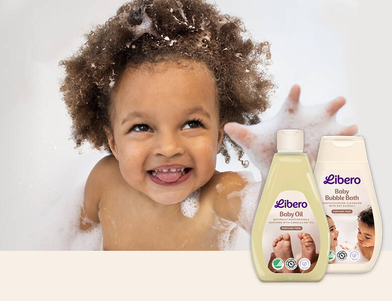 Her ses et glad lille barn, som er i karbad med en masse sæbeskum. I nederste højre hjørne ses to forskellige Libero plejeprodukter. 