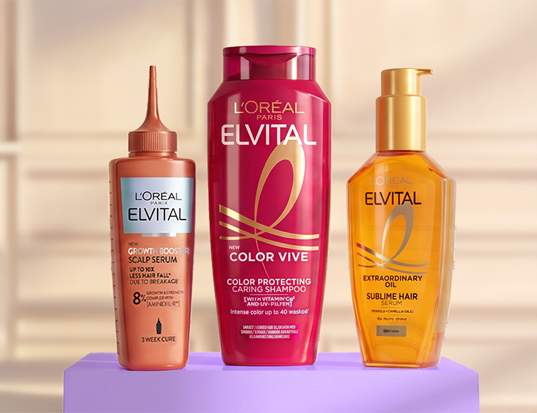 Her ses tre L’Oréal Paris Elvital hårplejeprodukter: Growth Booster Scalp Serum, Color Vive Shampoo og Extraordinary Oil Sublime Hair Serum på en lilla sokkel.