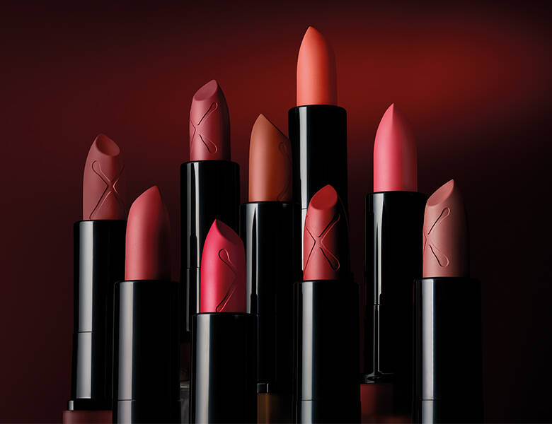 Her ses en masse forskellige læbestifter i røde nuancer. Baggrunden er dyb rød.