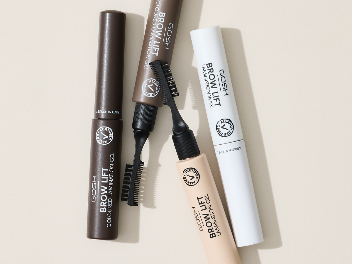 Her ses forskellige Brow Lift-produkter fra GOSH Copenhagen arrangeret mod en lys baggrund. Produkterne omfatter Coloured Lamination Gel og Lamination Wax i forskellige nuancer samt tilhørende brynbørster.