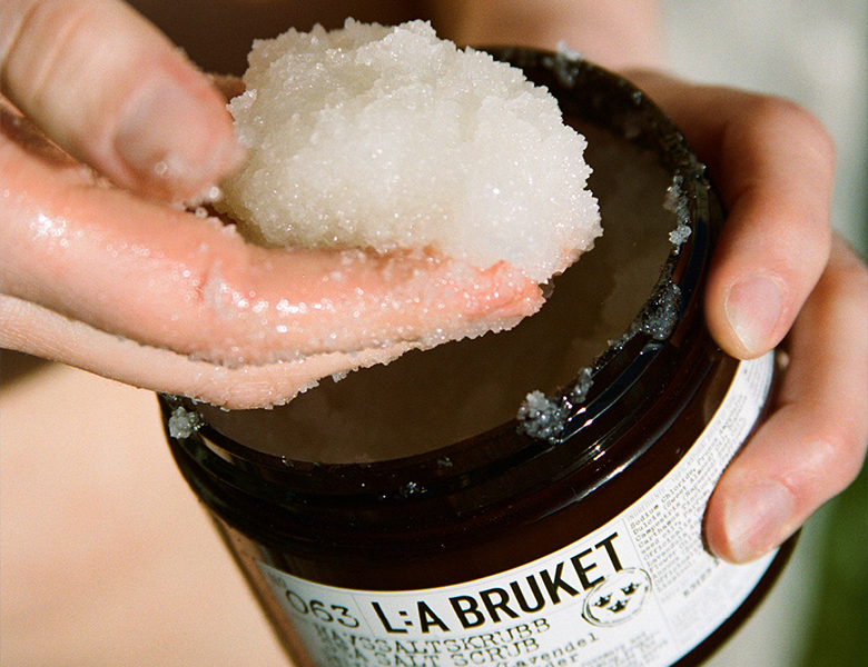 Her ses en hånd, der tager bodyscrub fra en krukke fra L:A BRUKET.