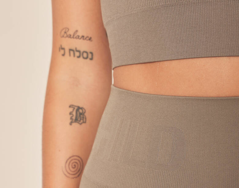 Her ses en kvinde i træningstøj i en neutral farve.