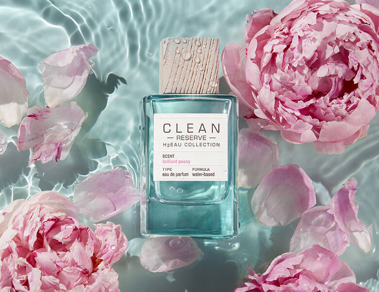 Her ses en blå Clean parfume flyde rundt i noget vand med lyserøde blomster. 