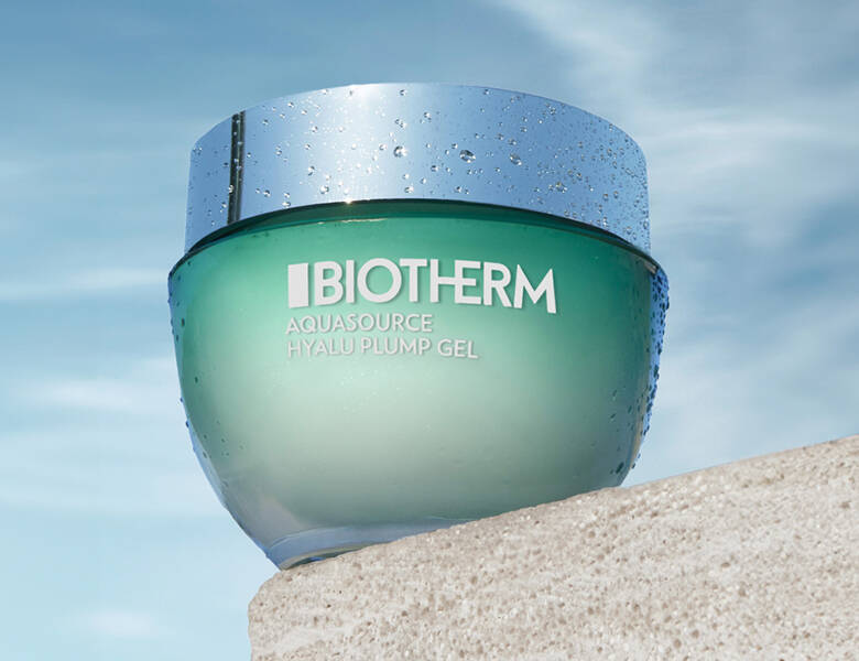 Her ses et grønt Biotherm produkt, som står på en sten med en blå himmel som baggrund. 