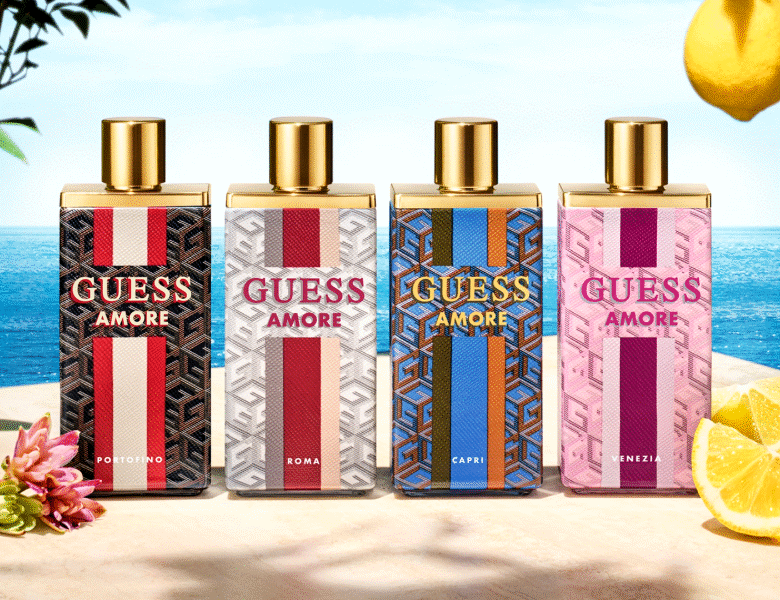 Her ses et billede med fire parfumeflakoner fra GUESS placeret side om side foran en havbaggrund. På flakonerne står teksten “GUESS AMORE” samt “PORTOFINO”, “ROMA”, “CAPRI” og “VENEZIA”. Flakonerne har forskellige mønstre og farver med guldfarvede låg.