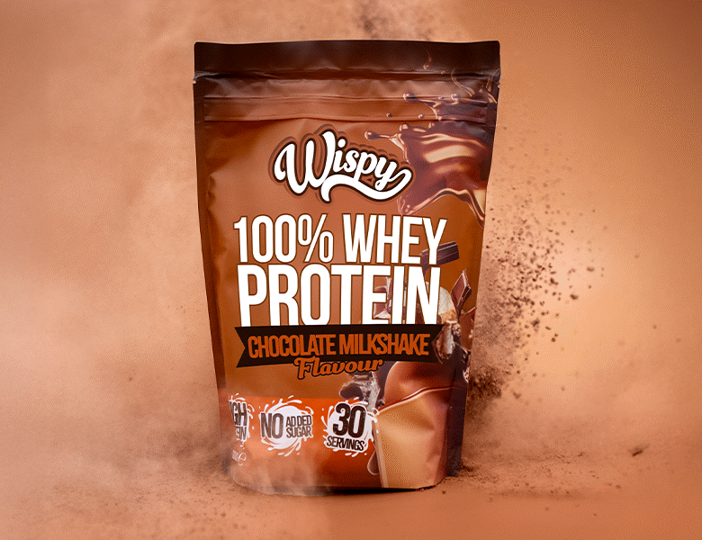Wispy Nutrition Proteinpulver brun med chokolade. Ses omgivet af chokoladepulver, der flyver rundt. Alt i brune farver også baggrunden.