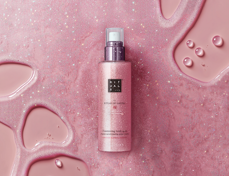 Her ses en lyserød og glimtende væske, hvori et lyserødt Rituals produkt ligger. 