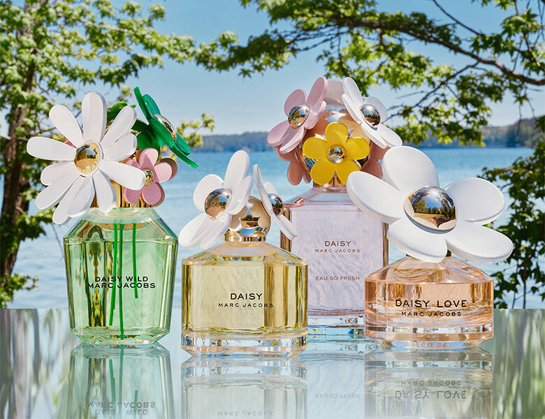 Her ses fire Daisy parfumer i forskellige farver. De står udenfor med havet i baggrunden.