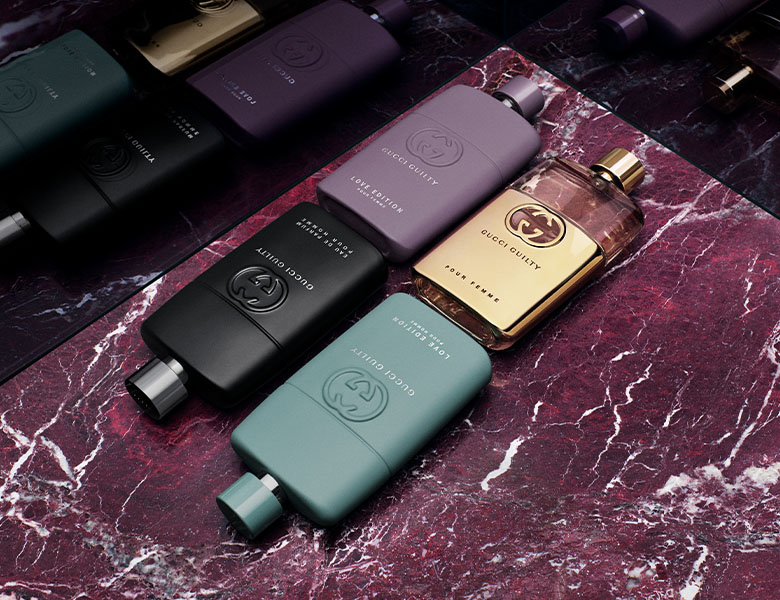 Her ses fire Gucci Guily parfumer der ligger på en mørkerød baggrund af marmor.