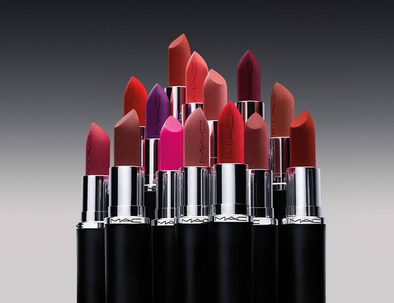 Her ses en mørkegrå baggrund med en masse forskellige MAC læbestifter i forskellige lyserøde, lilla og røde nuancer. 