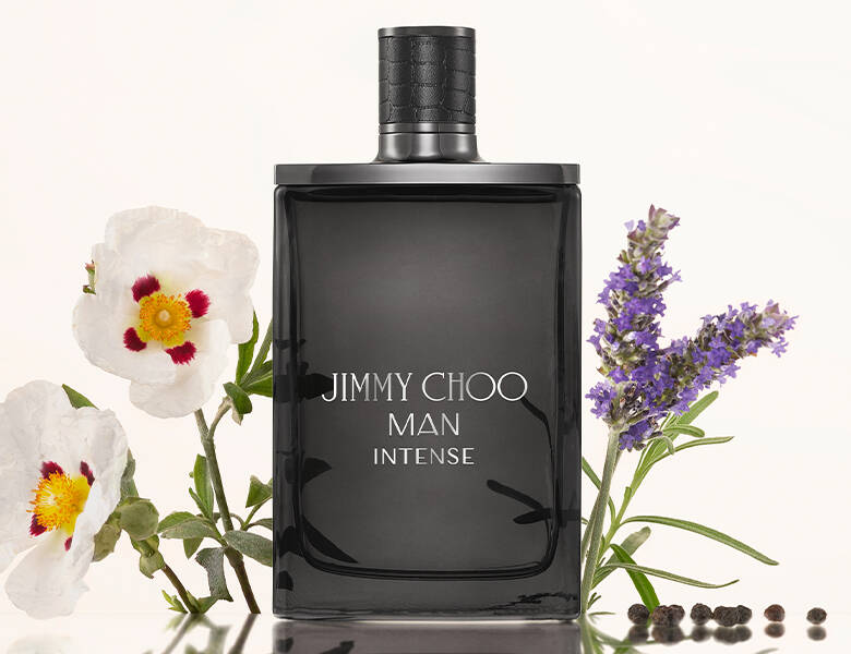 Her ses en hvid baggrund med nogle blomster. Forrest ses en sort Jimmy Choo parfume. 