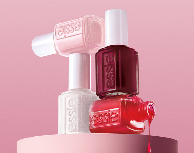 Her ses en lyserød baggrund med fire essie neglelakker; en hvid, en lyserød, en bordeaux og en rød.
