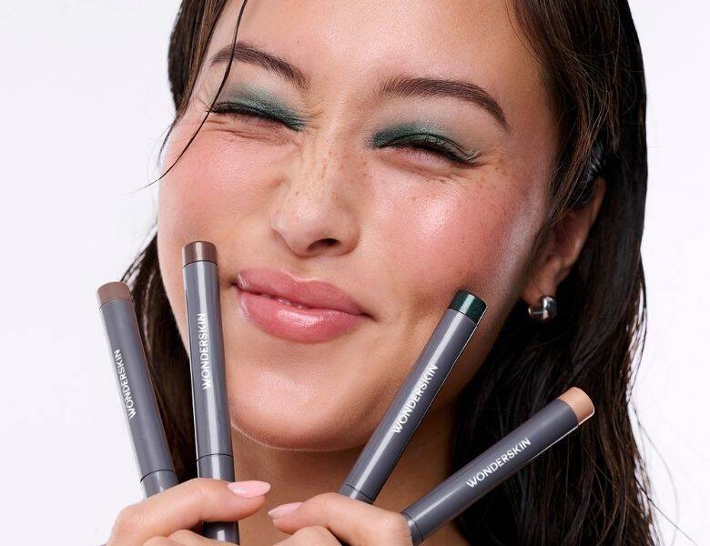 Her ses en glad kvinde med fire eyeshadow sticks i hånden.