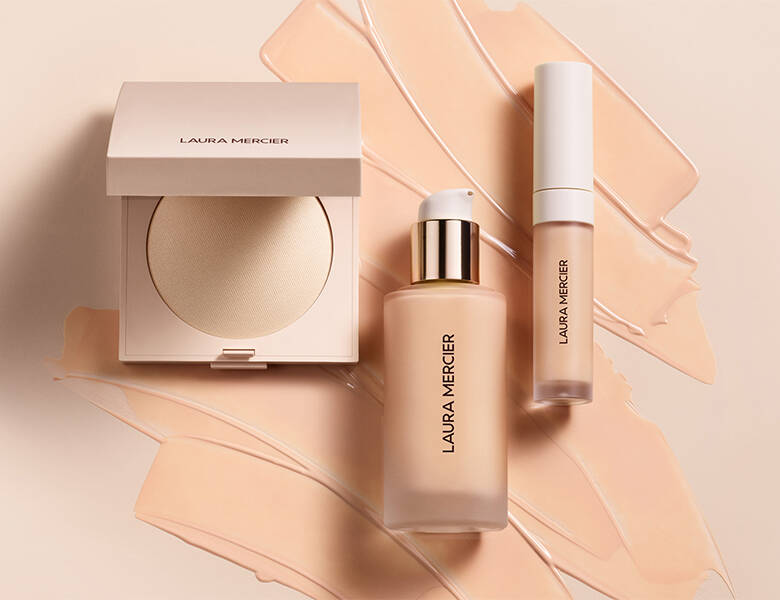 Her ses tre makeupprodukter, hvor selve produktet også er smurt ud på den beige baggrund.