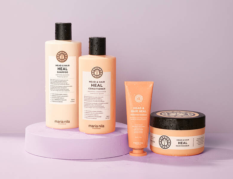 Her ses en lyselilla baggrund med fire orange Maria Nila produkter. 