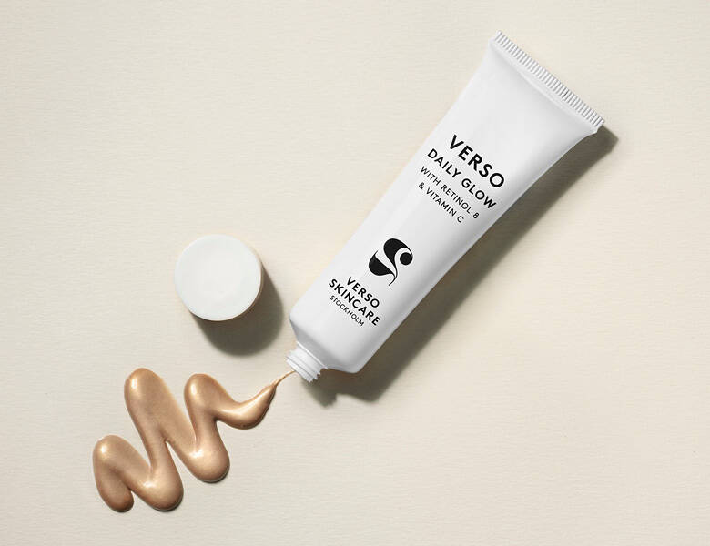 Her ses et hvidt Verso produkt, hvorfra der kommer en guldfarvet creme. Baggrunden er lys beige. 
