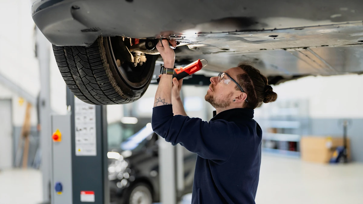 Kfz-Techniker führt Wartungs- oder Reparaturarbeiten am Unterboden eines Elektrofahrzeugs in der Werkstatt durch.
