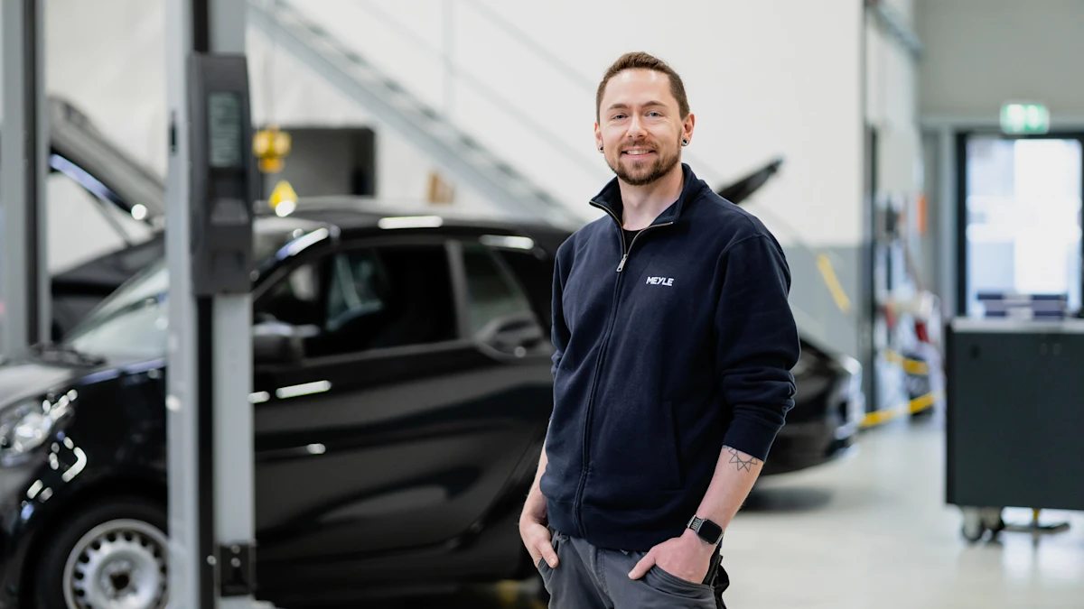 Roman Späth steht lächelnd mit den Händen in der Hosentasche in der EV Experience Werkstatt.